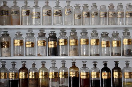 Etagères de récipients transparents anciens avec des étiquettes dorées contenant des parfums